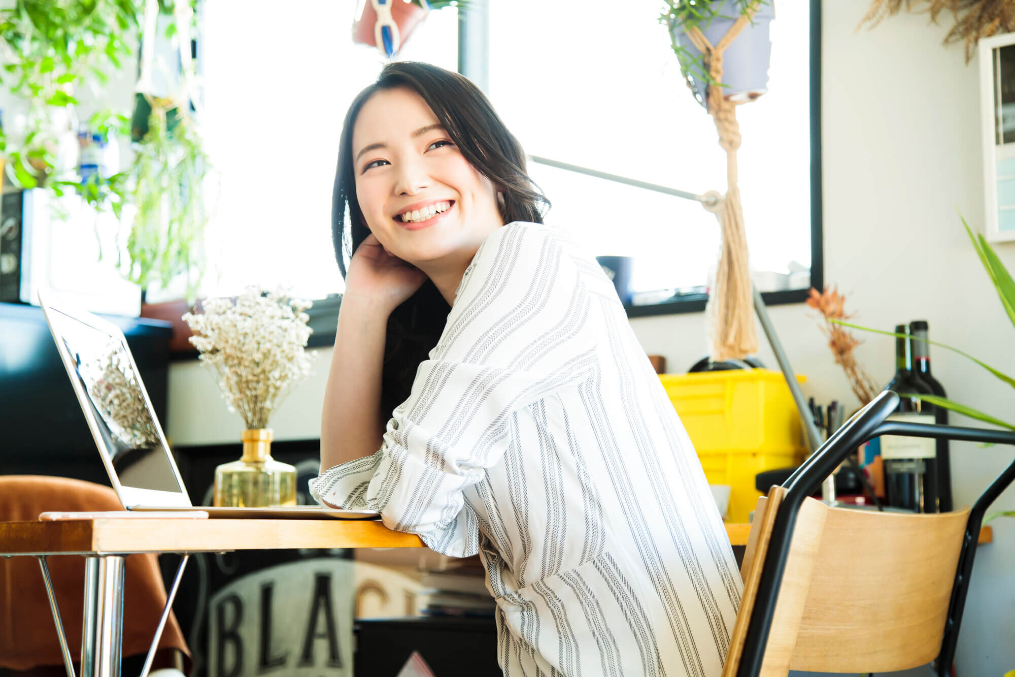 PCの前で笑顔でこちらを向いている女性の画像